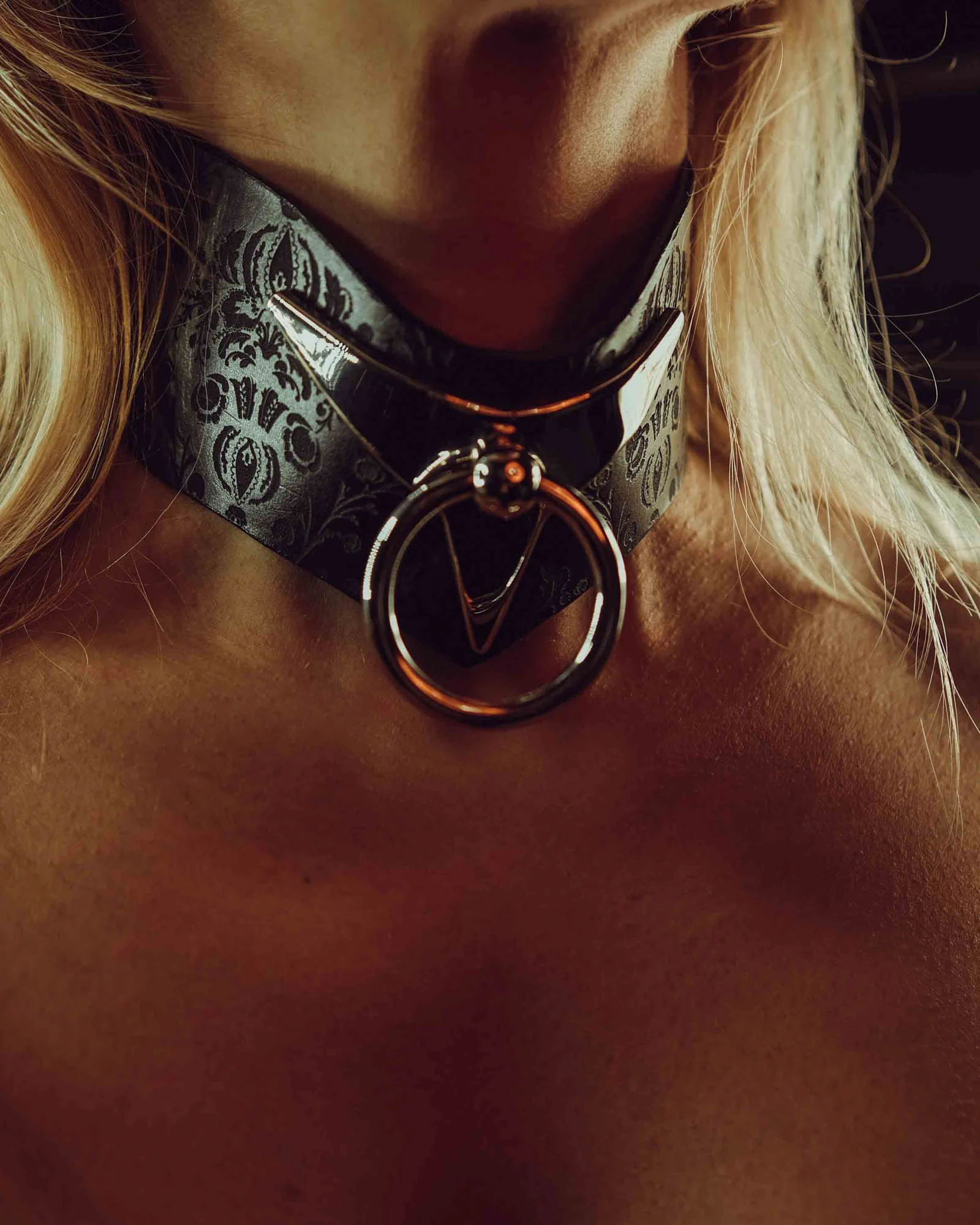Close-up of decorative leather collar with metallic ring on blonde creator neckline