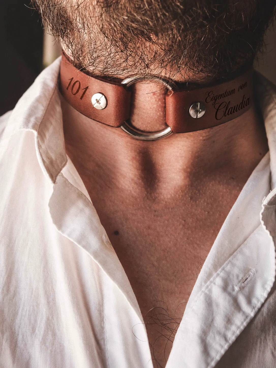 Artisan leather collar accessory with metal ring and white linen shirt